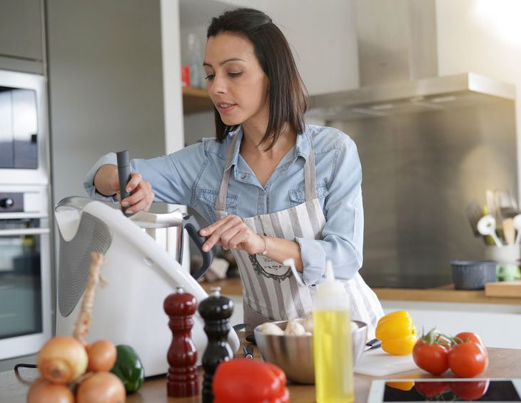Woman using kitchen robot to prepare dinner